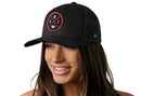 A woman with long brown hair smiles, wearing a Haka Hat Chicago Trucker Hat | Black CHI X Football Snapback featuring a round red, white, and black Chicago logo. The background is plain white.