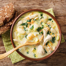 A bowl of creamy chicken and gnocchi soup with shredded chicken, gnocchi, spinach, and carrots, seasoned with SALTOPIA Infused Sea Salts' BUMPIN' CHICKEN & DUMPLINS Chicken and Herbs Seasoning. Served with seeded brown bread.