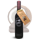 A bottle of Georgetown Olive Oil Co. Chocolate Coconut Balsamic Vinegar, made with aged balsamic vinegar from Modena, Italy, stands in front of a split coconut. A brown tag is tied around its neck and the Georgetown Olive Oil Co. label is visible on the bottle.