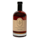 Under The Bark Syrup Co Cinnamon Maple Syrup is a clear glass bottle with a beige label and black cap, featuring rich amber syrup and a cinnamon stick inside for a unique, flavorful twist.