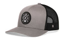 The Haka Hat Colorado Trucker Hat in gray and black features a mesh back and a round front patch with crossed lines, the letters C, O, L, and a triangle mountain design.
