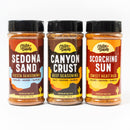 Three bottles of Chiles and Smoke Sonoran BBQ Combo (Pack of 3 Rubs) by Chiles and Smoke—featuring Sedona Sand (Fiesta Seasoning), Canyon Crust (Beef Seasoning), and Scorching Sun (Sweet Heat Rub)—are arranged side by side on a white background. This trio is the perfect grilling gift set, showcasing bold Sonoran BBQ seasoning flavors for any backyard cookout.