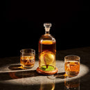 The Craftgen Baseball Decanter Set by Craftgen features a whiskey decanter with a baseball inside, two player-etched glasses, and a wooden base—all arranged on a dark surface under warm light for the perfect baseball gift.