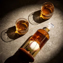 The Craftgen Baseball Decanter Set by Craftgen, filled with amber whiskey and featuring a baseball inside, sits on marble next to two whiskey-filled glasses—a perfect baseball gift for any fan.