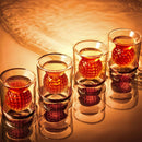 The Craftgen Golf Ball Shot Glasses - Set of 4 by Craftgen feature textured orange spheres and are arranged in a row on a reflective surface under warm, golden lighting.