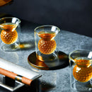 Craftgen Golf Ball Shot Glasses - Set of 4 by Craftgen are filled with whiskey and feature round, golf ball-textured ice spheres. A cigar on a metal holder completes this elegant, golf-themed barware display.