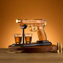 The Craftgen Gun Whiskey Decanter Set by Craftgen features a gun-shaped decanter with amber liquid on a stand, two filled shot glasses, gold bullets, and wheat stalks, making it an eye-catching addition to any home bar or a unique gift.