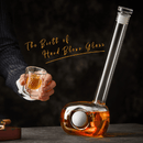 A suited individual holds a glass of whiskey beside the Craftgen Golf Decanter Set by Craftgen, shaped like a golf club head with an embedded ball and filled with amber liquid. Text: The Birth of Hand Blown Glass—a perfect whiskey gift.