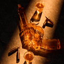 The Craftgen Gun Whiskey Decanter Set by Craftgen features a gun-shaped decanter filled with whiskey, displayed on a dark surface with three bullets and two glasses, all illuminated by dramatic lighting.