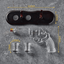The Craftgen Gun Whiskey Decanter Set by Craftgen, featuring a gun-shaped decanter, two shot glasses, and a black display stand, is arranged on gray marble with yellow lines showing their measurements in inches.