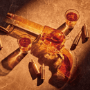The Craftgen Gun Whiskey Decanter Set by Craftgen features a pistol-shaped glass decanter filled with amber whiskey, three matching shot glasses, and brass bullets, all displayed on a marble surface under warm lighting.