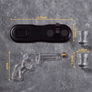 The Craftgen Gun Whiskey Decanter Set by Craftgen features a glass revolver decanter below a black compartment tray, with two shot glasses on the right. Yellow text shows dimensions on a gray marble surface—ideal for western-themed barware collections.