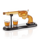 The Craftgen Gun Whiskey Decanter Set by Craftgen features a western-style glass gun decanter on a black stand with two matching shot glasses, perfect for serving and displaying your favorite whiskey.