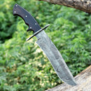 The Texan Knives Custom Handmade 13" American-Made Damascus Steel Bowie Knife with a Rosewood Handle and Leather Sheath is embedded in a tree branch, set against blurred green foliage.