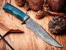 The Texan Knives Custom Handmade 13" Damascus Steel Confederate Civil War Bowie Knife, featuring a camel bone handle and leather sheath, rests on a wooden surface amid pine cones, wood pieces, and rocks.