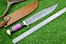 The Texan Knives Damascus Steel "The Bowie Knife" features a 16" blade, brass guard, and resin pakkawood handle. Shown with a metal ruler and leather sheath on grass.