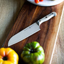 A Messermeister kitchen knife with a Custom Driftwood Mod Kit Handle - Small rests on a dark wooden cutting board, surrounded by heirloom tomatoes on the board and table.