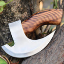 The Texan Knives Forged Pizza Cutter features a custom handmade J2 steel blade and smooth wood handle, displayed outdoors resting against the trunk and branch of a tree.