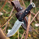 The Premium Custom Handmade Damascus Skinner Knife by Texan Knives features a wangi wood handle and distinct wave-like patterns on the blade. A brown leather sheath in the background highlights this artisan skinner knife’s craftsmanship.