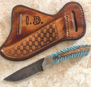 The Texan Knives Custom Handmade Damascus Steel Belt Knife features a pine cone resin handle and comes with a leather sheath, making it perfect for fall adventures—displayed together on a light marble surface.