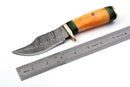 The Texan Knives Custom Handmade Damascus Skinning Knife features a patterned blade and an orange-green camel bone handle, shown beside a ruler with inch and centimeter marks. Perfect gift for hunters by Texan Knives.