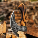 A close-up of the Texan Knives Custom Hand-Engraved Pizza Axe features an 8-inch J2 steel blade with engraved skull and runic designs, plus a patterned wooden handle, resting on split logs with firewood in the background.