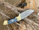 The Texan Knives Hunting Knife features a 9" forged Damascus steel blade, a Pakka wood handle with brass bolster, and comes with a leather sheath—an eye-catching addition to any premium hunting knife or outdoor gear collection.