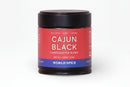 A jar of World Spice Cajun Black by World Spice, featuring a red label and black lid with the words PICANTE • HEAT • UMAMI and WORLD SPICE at the bottom. This bold bayou blend delivers authentic Cajun spices and robust blackening seasoning to your kitchen. Net weight: 1.83 oz (52g).