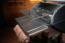 Two metal slide-out grill racks from the Pimp My Grill® Gen2 Slide-Out Rack System for Camp Chef Woodwind 24 / Woodwind Pro 24 / CL 24 installed in a pellet grill, with a roll of butcher paper resting on the bottom rack.