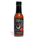 A bottle of California Hot Sauce Solutions J's Small Batch The Exorcist Hot Sauce featuring a black label with red, evil-looking eyes and text emphasizing no sugar and no preservatives.