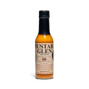 A bottle of California Hot Sauce Solutions J's Small Batch Mustard Glen Hot Sauce from California Hot Sauce Solutions, made with Islay single malt whisky, featuring a black cap and a beige label with black text, standing upright on a white background.