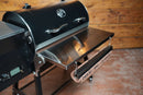 A black Recteq Patio Legend 410 pellet grill featuring a Pimp My Grill® Tactical Stainless Folding Front Shelf with an attached paper towel dispenser.