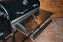 Pimp My Grill® Tactical Stainless Folding Front Shelf attached to a Recteq Patio Legend 410, featuring a paper towel holder with branded parchment paper underneath to maximize grill prep space.