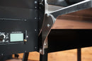 Close-up of a Pimp My Grill® Tactical Stainless Folding Front Shelf attached to the front of a black RecTeq Patio Legend 410 grill with a digital display panel.