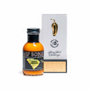 A bottle of California Hot Sauce Solutions Hip Bone South Carolina BBQ Sauce, famous for its spicy twist on traditional mustard-based BBQ, sits beside a white Spicy Food Productions box topped with a gold pepper-shaped trophy and text celebrating its Fiery Food Challenge award.