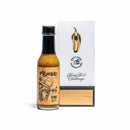 A bottle of California Hot Sauce Solutions CHSS Mexicali Verde Hot Sauce stands beside a Spicy Food Challenge trophy with a golden pepper and an engraved plaque awarded in 2023.