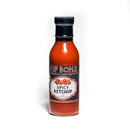 A bottle of California Hot Sauce Solutions Hip Bone Spicy Ketchup by California Hot Sauce Solutions, made with organic ketchup and a touch of scorpion pepper, is shown with a black cap and a decorative label featuring vivid red pepper graphics, set against a white background.