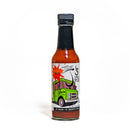 A glass bottle of California Hot Sauce Solutions J's Small Batch Taco Hot Sauce features a green food truck illustration on the label, which reads “Taco” and highlights that it contains no sugar or preservatives. This reddish-orange sauce from California Hot Sauce Solutions is perfect for adding a flavorful kick to your favorite dishes.