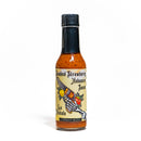 A bottle of California Hot Sauce Solutions CHSS La Pistola Hot Sauce by California Hot Sauce Solutions, labeled with an illustration of a hand holding a pistol surrounded by strawberries, peppers, and flames on a cream background. This bold hot sauce delivers a unique fusion of sweet strawberries and fiery habanero for an unforgettable spicy strawberry sauce experience.