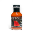 A glass bottle of California Hot Sauce Solutions Hip Bone Kansas City BBQ Sauce, featuring a black cap, vibrant red sauce inside, and a label adorned with a Kansas City map and the slogan “Connected to Your Mouth Bone.” Crafted by California Hot Sauce Solutions, this fiery condiment delivers the bold character and smoky sweetness of authentic Kansas City BBQ in every drop.