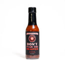 A glass bottle of California Hot Sauce Solutions Paulman Acre Don’t Pear the Reaper Hot Sauce, topped with a black cap and displayed against a plain white background—showcasing the bold heat of Carolina Reaper peppers.