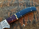 Close-up of a Texan Knives Custom Handmade Damascus Fillet Knife, with a 13-inch blade and a buffalo horn & rosewood handle, featuring brass rivets and bolster, resting on a textured brown surface.