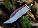 The Texan Knives 13-Inch Damascus Steel Cowboy Bowie Knife features a patterned blade, buffalo horn handle, and comes with a leather sheath—ideal for knife enthusiasts and displayed beautifully on weathered wood with moss.