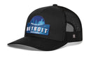 The Haka Hat Detroit Motor City Trucker Hat is a black mesh snapback featuring a blue and white "Motor City Detroit Michigan" patch and embroidered skyline cityscape.