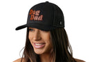 A woman with long brown hair wears the Haka Hat Dog Dad Trucker Hat Leather in black, featuring bold brown and orange letters. This signature Haka Hat Black Paw Snapback stands out against the plain white background.