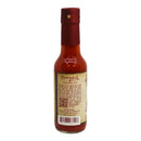A bottle of Powerful Pepper Dr. Gleaton's Chili Elixir Barrel Aged Hot Sauce from Powerful Pepper Company features a red cap and a beige label displaying the brand’s name, various text details, a QR code, and a barcode. The vibrant red-orange sauce inside highlights the signature appearance of an authentic Louisiana style hot sauce.