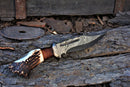 The Texan Knives Custom Handmade 13" Damascus Bowie Knife, featuring a stag crown and rosewood handle with leather sheath, is displayed on weathered wood with rusty metal parts scattered in the background.
