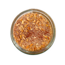 A glass jar of SALTOPIA Infused Sea Salts' Saltopia Paprika & Onion Salt: EUREKA SWEET PAPRIKA, featuring sea salt, dried garlic, and reddish spices, viewed from above on a white background.