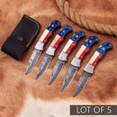 Five Texan Knives Exclusive Texas Flag Damascus Steel Pocket Knives, each with a 3" blade and colorful handles, are displayed on animal hide beside a leather sheath and rope. "LOT OF 5" is shown at the bottom right—ideal for collectors.