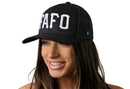 A woman with long brown hair smiles while wearing the Haka Hat FAFO Trucker Hat, a stylish black snapback from Haka Hat featuring bold "Fuck Around, Find Out" 3D embroidery, shown against a plain white background.